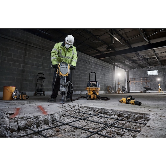 DEWALT D25966, D25966-B2 showcased at work in a construction site, breaking concrete floor with safety gear.