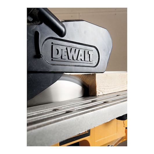 Close-up of a DEWALT saw cutting a piece of wood on a workstation.