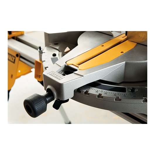 Close-up view of a DEWALT miter saw, highlighting the adjustment knob and angle scale on the base.