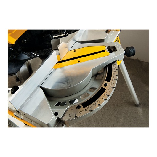 Close-up image of a DEWALT miter saw showing the adjustable angle scale and fence for precise cutting.
