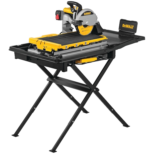A DEWALT D36000 wet tile saw with stand, featuring a yellow and black color scheme. The saw is mounted on a sturdy foldable stand and has a cutting table with guides. The DEWALT logo is visible on both the saw and the side support tray.