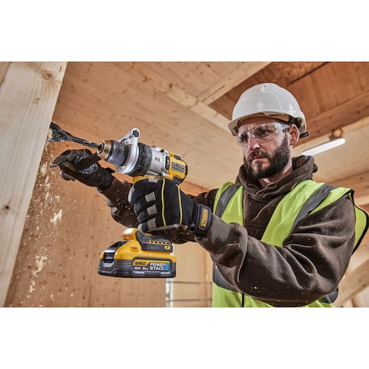 DEWALT drill in use, showing DCD1007NT and DCZ607X2-XE SKUs. Worker in safety gear drilling wood.