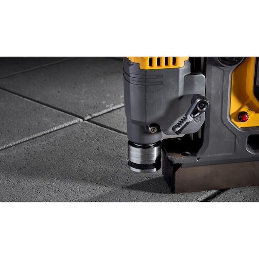 Close-up of a DEWALT drill press positioned on gray concrete tiles.
