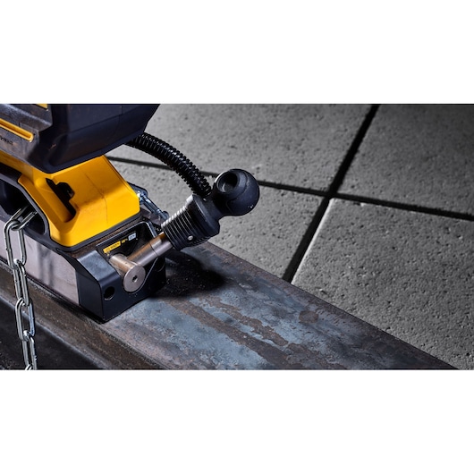 Close-up of a DEWALT tool attached to a metal beam with a chain, on a concrete floor.