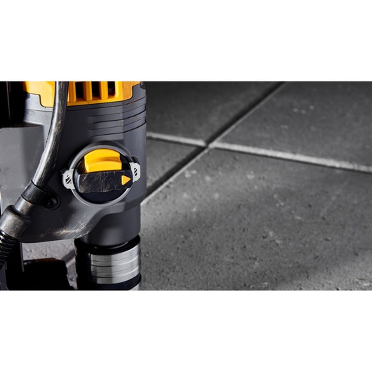 Close-up of a DEWALT power tool with yellow and black dial, placed on grey tiled flooring.