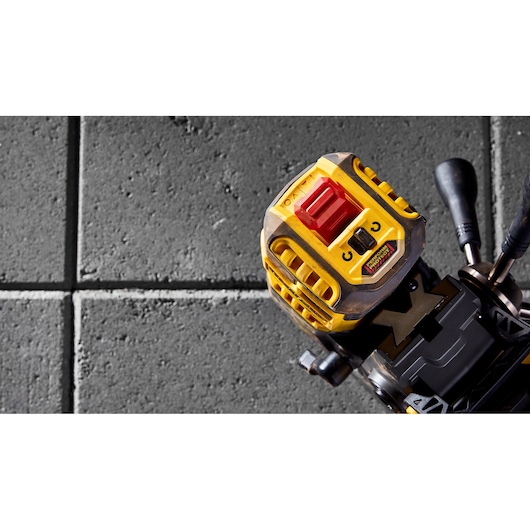 Close-up of a DEWALT yellow tool on grey tiles, showing the control switches and sturdy design.