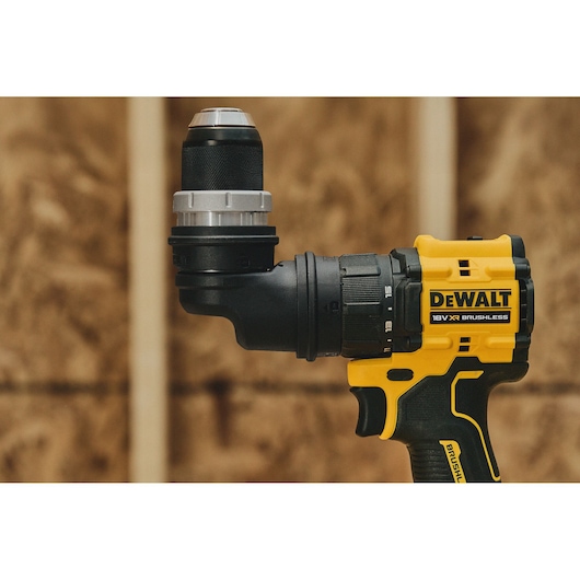 Close-up view of a DEWALT 18V XR Brushless cordless drill with an adjustable side handle, shown against a construction background.