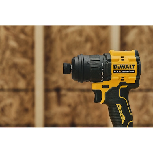 A close-up image of a yellow and black DEWALT 18V XR brushless cordless drill, shown against a blurred wooden background.