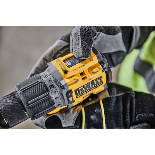 Close-up of a gloved hand adjusting the speed setting on a DEWALT 18V XR Brushless cordless drill. The drill features a yellow and black design and visible brand markings.