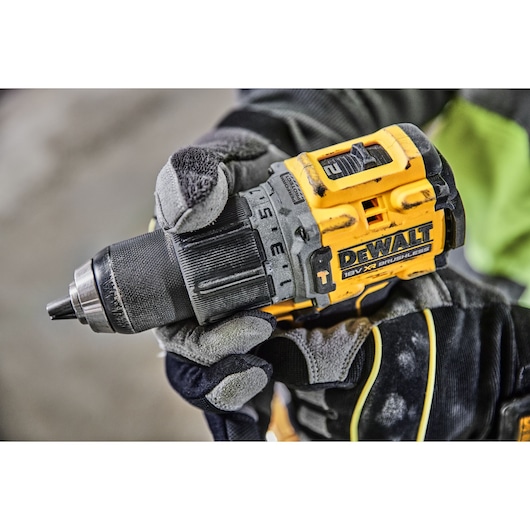Close-up of a gloved hand holding a DEWALT 18V XR brushless cordless drill.