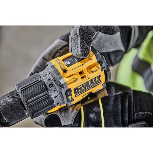 Gloved hand adjusts settings on a DEWALT 18V XR brushless drill.