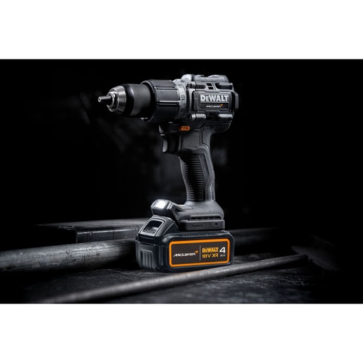 A DEWALT cordless power drill with an 18V XR 4Ah battery, featuring McLaren branding, placed on a dark industrial surface.