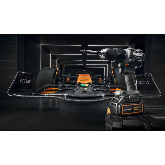 A DEWALT cordless drill is prominently displayed in the foreground, with a Formula 1 race car in orange and black colors positioned in the background inside a modern, illuminated garage tunnel.