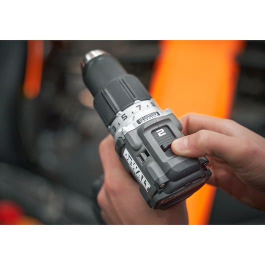 Hand adjusting a DEWALT cordless drill with visible speed settings and control dial.