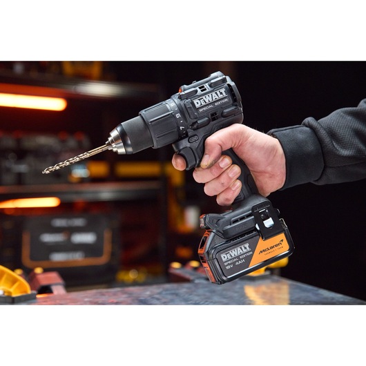 A hand holds the DEWALT x McLaren F1 Team 18V XR Special Edition Hammer Drill Driver with 4Ah battery