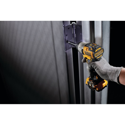 DEWALT DCK2111L2T-XE and DCF801N drill used on a metal door hinge. Photography product image.