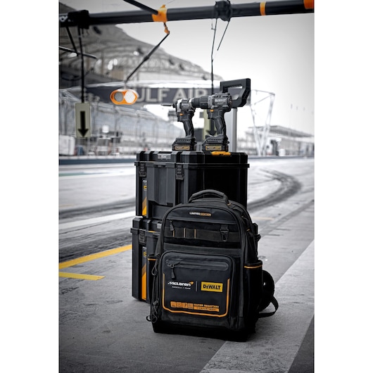 A DEWALT limited edition tool set is pictured, including a black and yellow backpack, two cordless power tools on top of a stack of black storage cases, with a racing track in the background.