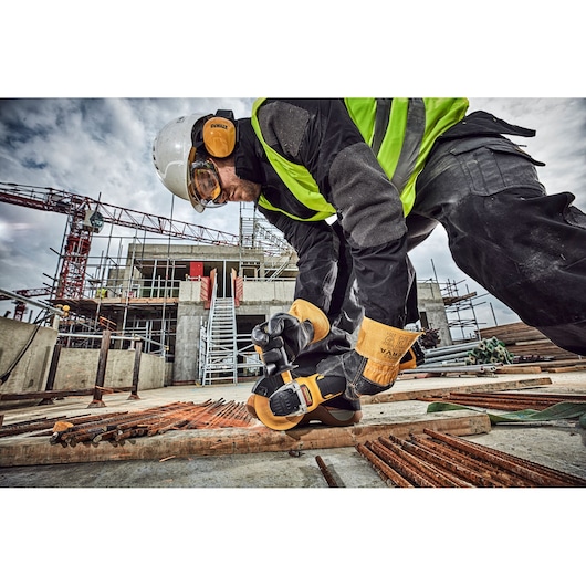 Worker using DEWALT tool on site. SKUs: DCG406N, DCZ409P2-XE, DCZ401P3-XE, DCG406. Photography category.