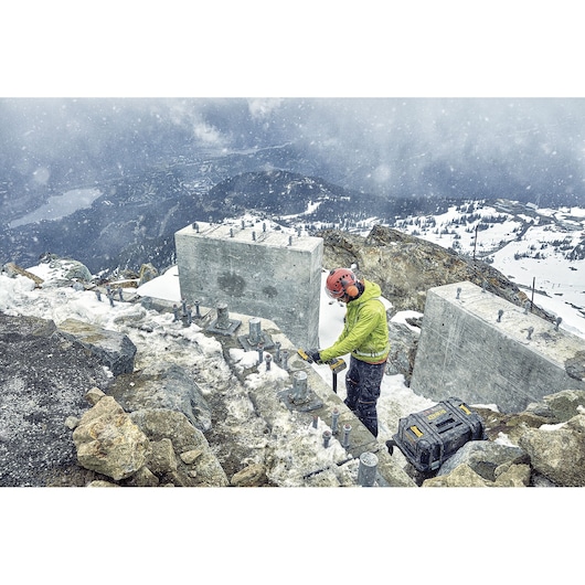DEWALT DCZ507T2-XE, DCG418N, DCZ503X2-XE used outdoors in snowy mountain construction. Photography product image.