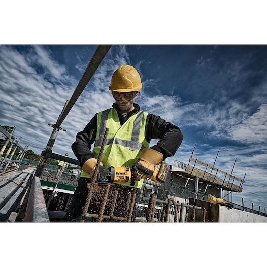 Worker uses DEWALT tool on site. SKUs: DCZ507T2-XE, DCG418N, DCZ503X2-XE. Photography product category.