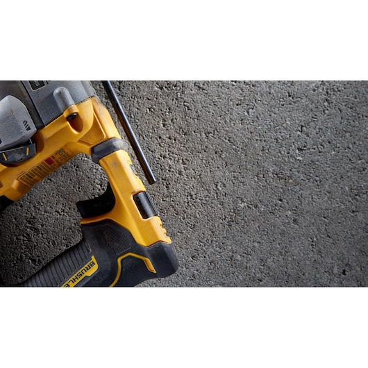 Close-up view of a yellow and black DEWALT power tool, partially visible, placed on a rough concrete surface.