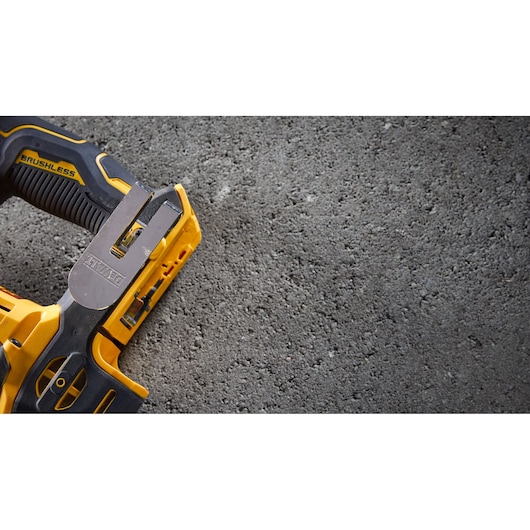 Close-up view of a DEWALT brushless power tool on a rough concrete surface, showing the handle and part of the tool in yellow and black.