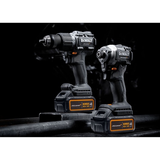 Two DEWALT cordless power tools, including a drill and an impact driver, are shown with McLaren-branded 18V XR 4.0Ah batteries. The tools are black and orange and are positioned against a dark background.