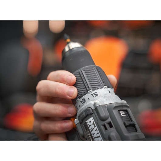 Close-up of a person holding a DEWALT cordless power drill, focusing on the adjustable torque settings and the hand gripping the tool.