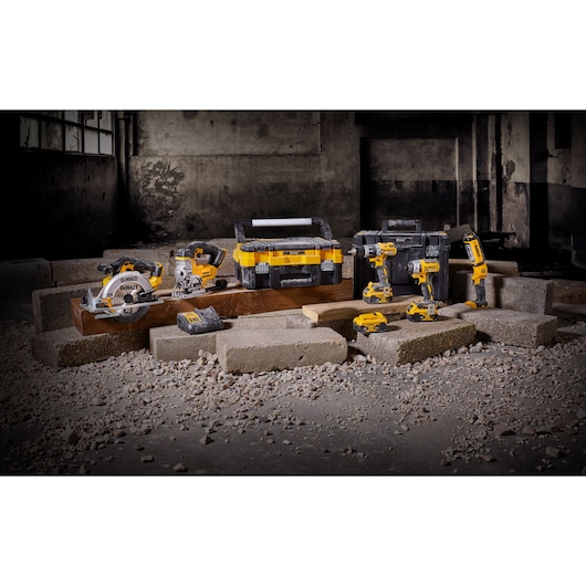 DEWALT cordless tool set with toolbox and batteries displayed on blocks in an industrial setting.