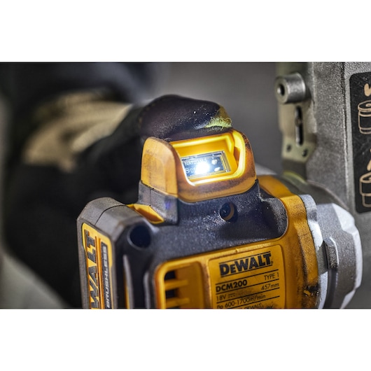 Close-up of a DEWALT DCM200 tool with indicator light illuminated during use.