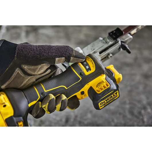 Gloved hand adjusting settings on DEWALT cordless power tool with yellow and black handle.