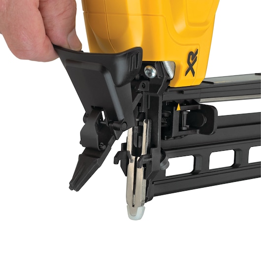 Close-up of a hand adjusting a DEWALT XR nail gun, focusing on the trigger and loading mechanism.