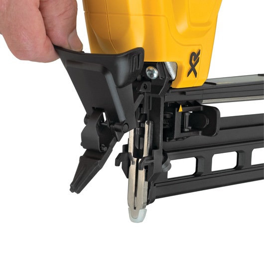 Close-up of a DEWALT nailer being operated, showing hand adjusting the tool’s front mechanism.