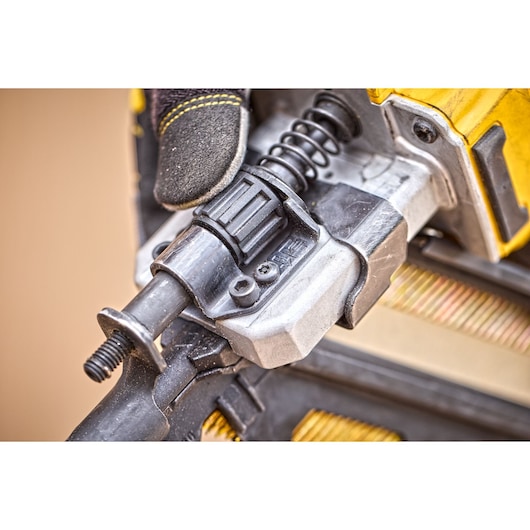 Close-up of a DEWALT power tool part with a gloved hand, showing mechanical details and spring mechanism.