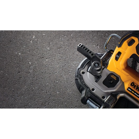 Close-up of a DEWALT power tool, yellow and black, on a textured surface, showing part of handle and base.