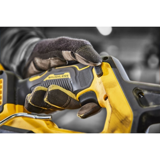 Close-up of a gloved hand operating a DEWALT brushless power tool, highlighting the grip and control buttons.