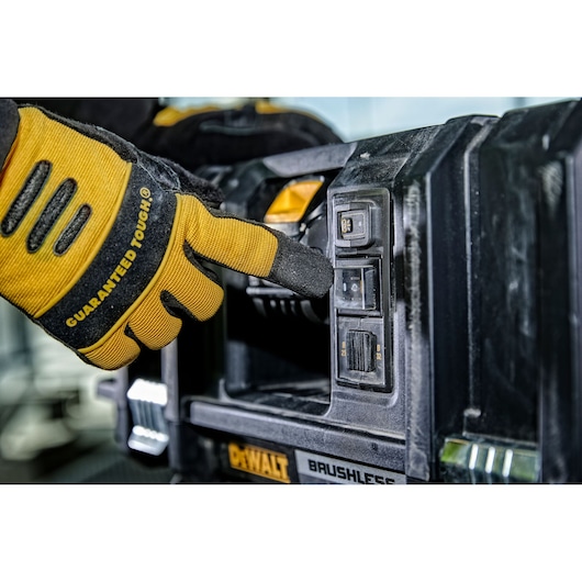 A gloved hand presses a button on a DEWALT brushless power tool, focusing on the control panel and branding details.