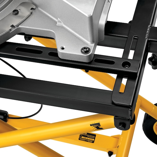 Close-up view of a DEWALT miter saw stand, featuring sturdy yellow metal frame and black mounting brackets with a silver tool mounted on top.