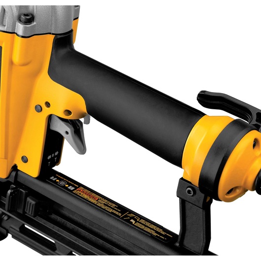 Close-up image of a DEWALT pneumatic nail gun, showing the handle, trigger, and part of the yellow and black body with warning labels.