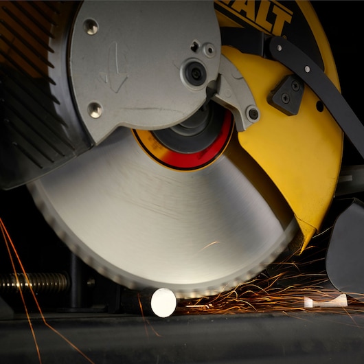 Close-up view of a DEWALT power saw cutting through a metal rod, with sparks flying as the blade makes contact.