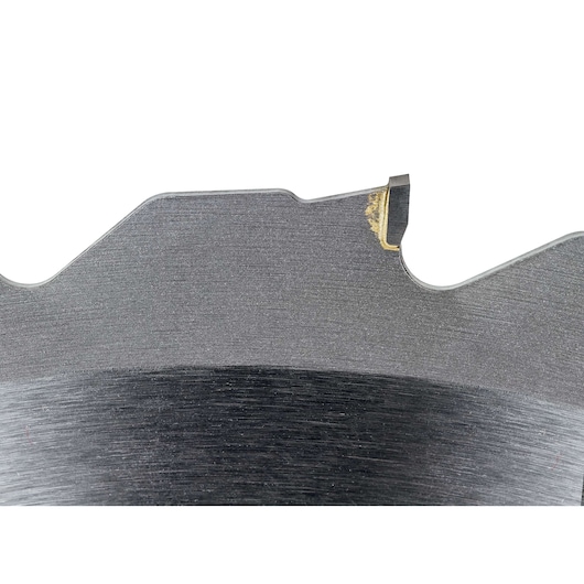 Close-up view of a section of a DEWALT circular saw blade, showing the metal surface and one carbide-tipped cutting tooth. The image highlights the tooth detail and the blade material.