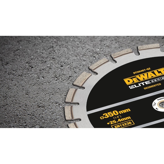 Close-up of a DEWALT segmented circular saw blade from the Elite Series, partially embedded in a rough concrete surface. The blade is labeled DT20467-QZ and indicates specifications of 350mm diameter and 25.4mm arbor size.