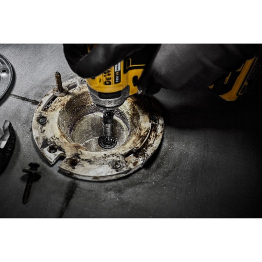 DEWALT tool used for drilling or grinding inside a circular metal fixture on a work surface.