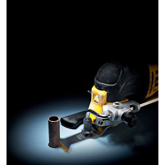 A DEWALT oscillating multi-tool with cutting accessory attached, shown cutting through a metal pipe on a dark background.