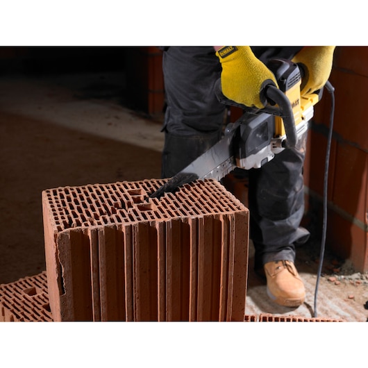 Person using a DEWALT saw to cut through a hollow construction brick in a work area.