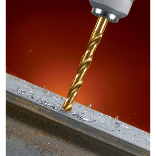 A close-up of a gold-colored drill bit attached to a power tool, drilling into a metal surface with metal shavings visible around the hole.