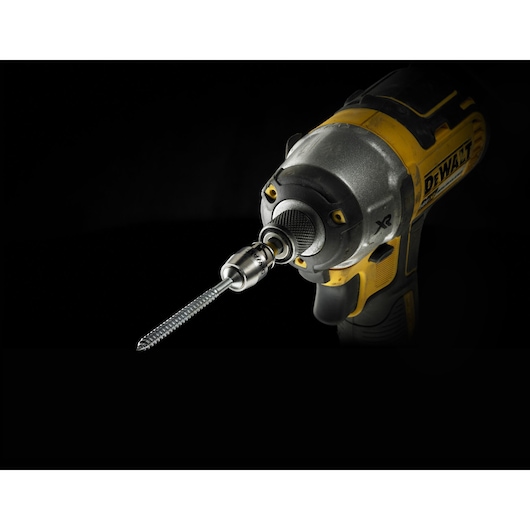 Close-up view of a DEWALT power drill equipped with a spiral drill bit against a dark background.