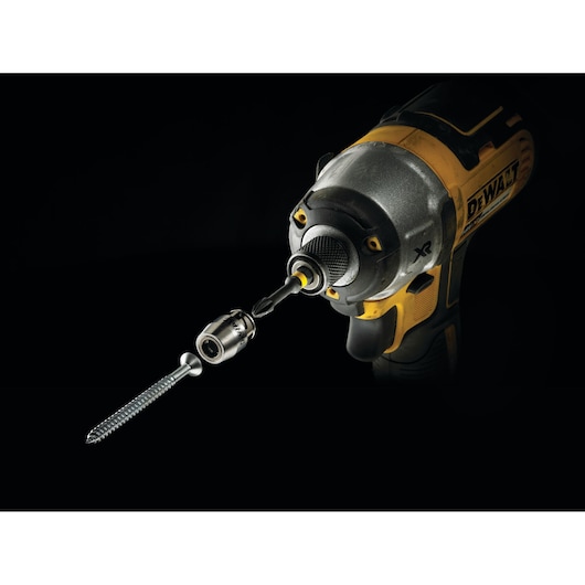 Close-up of a DEWALT power tool with a screwdriver bit and magnetic screw lock attachment holding a screw, shown against a black background.