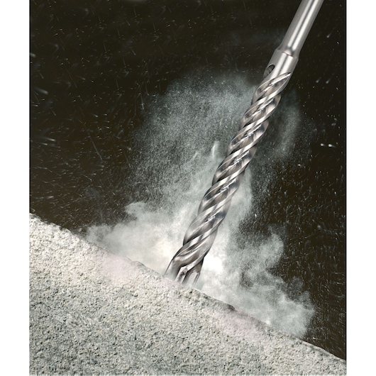 Close-up of a metallic drill bit penetrating concrete, dust and debris flying around.