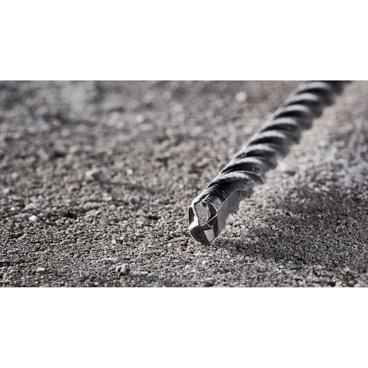 Close-up of a DEWALT DT8935 rotary hammer drill bit lying on a rough concrete surface.